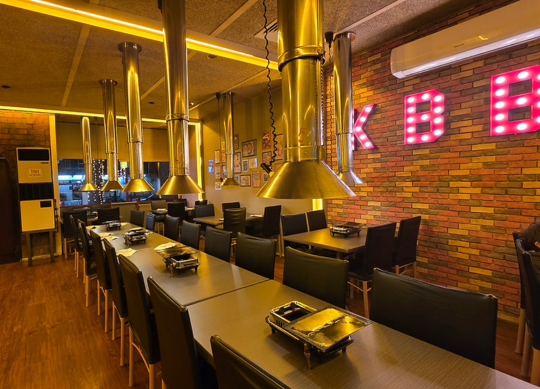 Warm, cozy Korean BBQ restaurant interior with tables and exhaust hoods, landscape