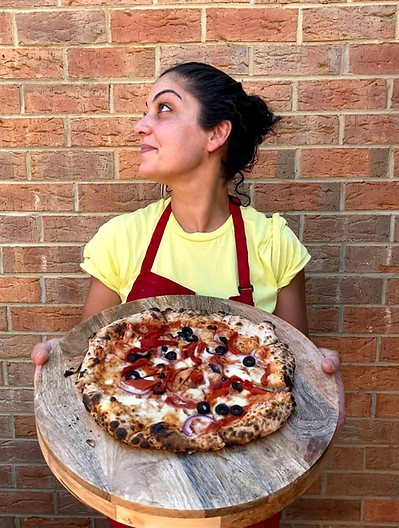 miss dough pizza chef holding a vegetarian woodfired pizza