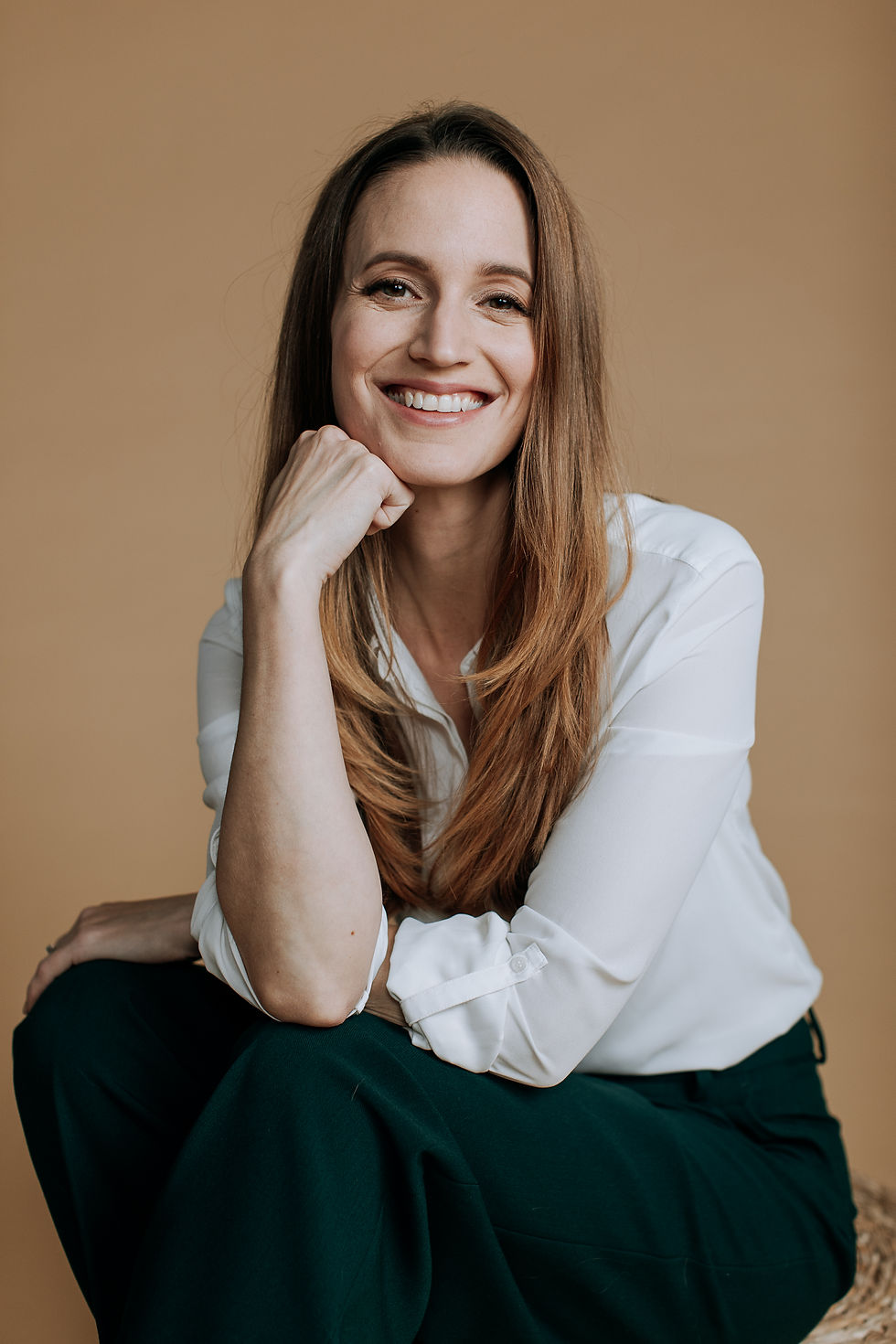 Anna Koskinen nojaa käteensä ja hymyilee.