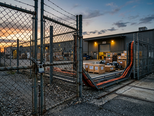 Wide-angle view of a locked warehouse gate with connected cables running through it