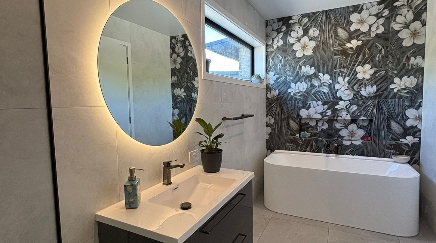 Modern bathroom with illuminated mirror, floral wallpaper, and floating vanity