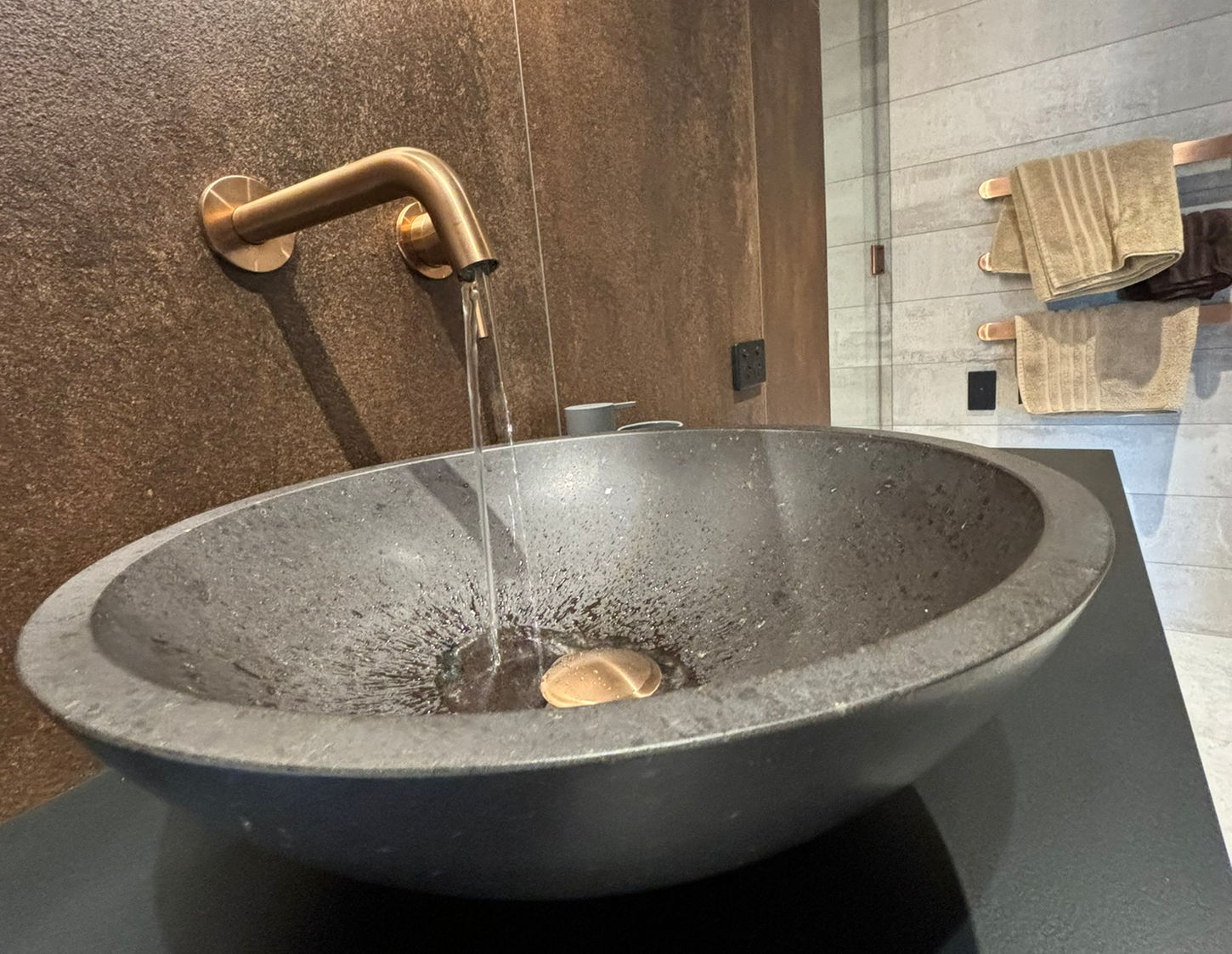 Dark stone vessel sink with gold faucet