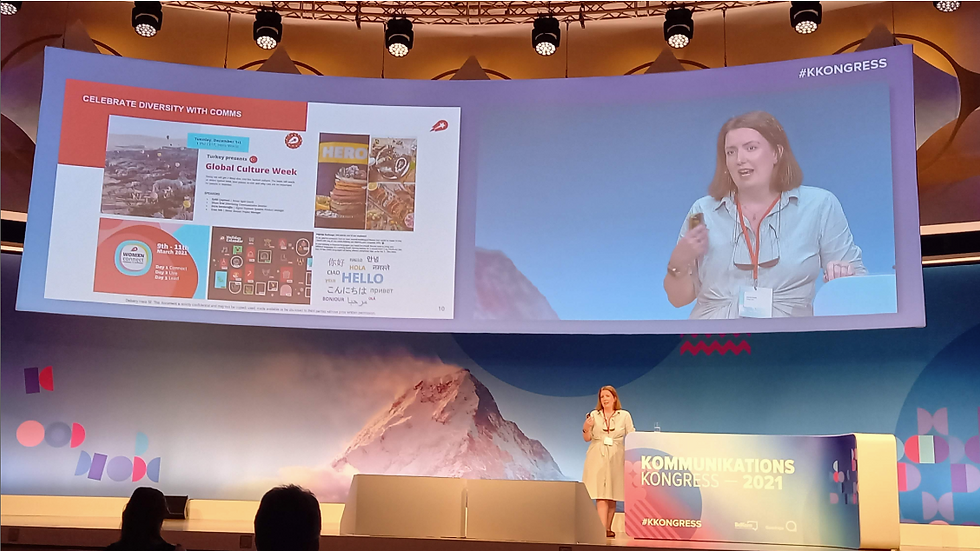 Woman presenting on a stage at a communications conference