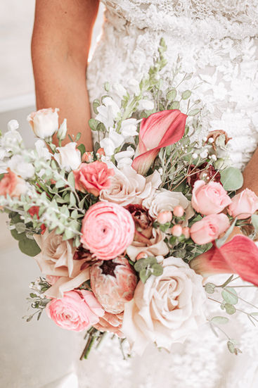Bride holding a beautiful bouquet of pink and white roses during wedding ceremony.