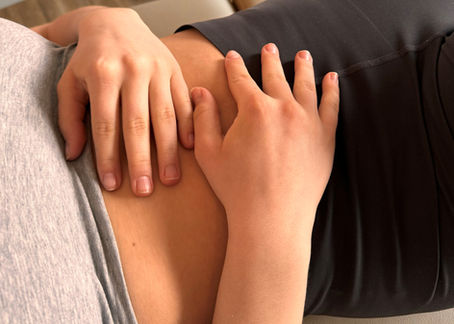 Hände ruhen achtsam auf dem Bauch aufgrund von unerklärlichen Bauchschmerzen – sanfte Selbstwahrnehmung und Unterstützung der Körperarbeit bei ganzheitlicher Behandlung