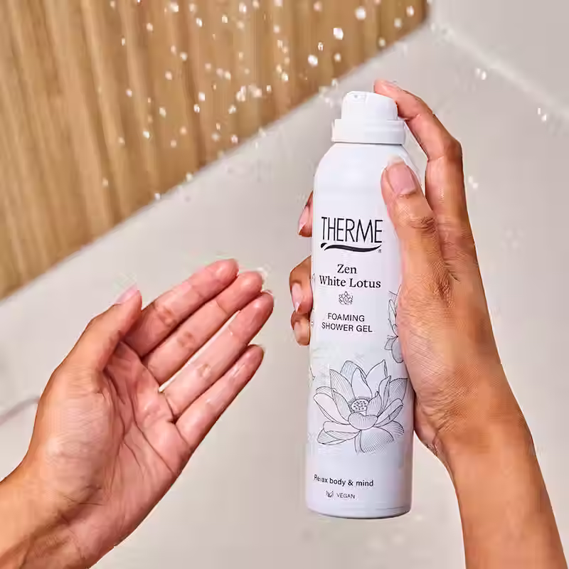 Miniatura: Aplikacja pianki pod prysznic Therme Zen White Lotus – kobieta trzyma opakowanie i nakłada delikatną piankę na dłoń.