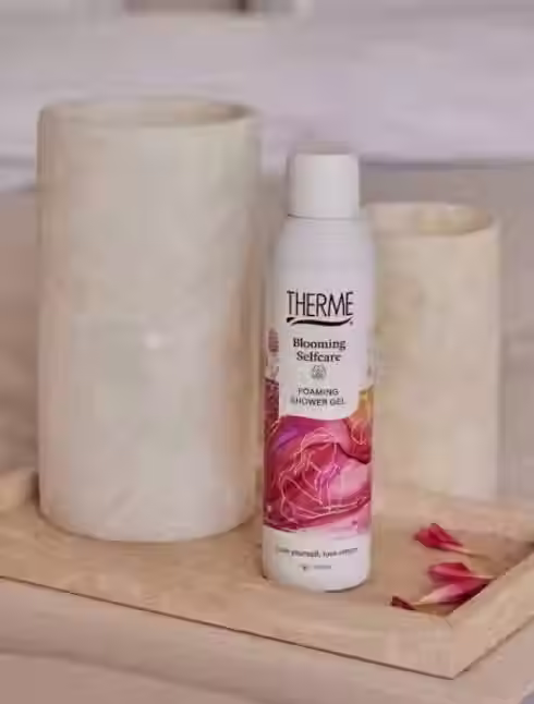 Pianka pod prysznic Therme Blooming Selfcare na eleganckiej tacy z kamienia, otoczona płatkami kwiatów – idealna do zmysłowego, relaksującego rytuału pielęgnacyjnego.