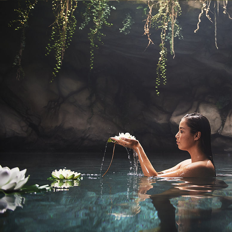 Kobieta biorąca kąpiel w źrodle z kwiatami lotosu - naturalne pielęgnacja od LaWell.pl
