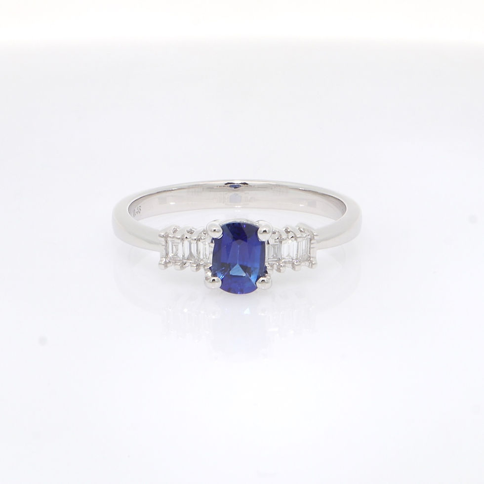 Classic oval gemstone ring with three-stone baguette diamond accents on a gold band.