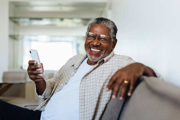 Smiling senior man using a smartphone on a couch