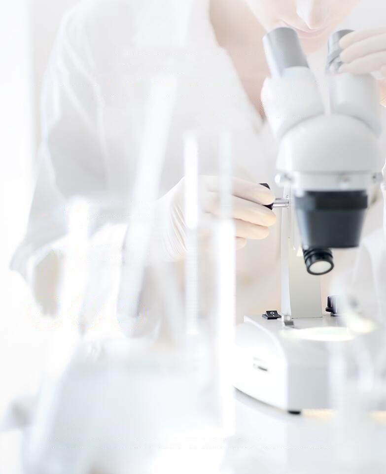 Scientist in white lab coat using a microscope