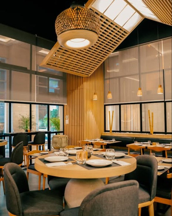 The interiors of Mitsu-Ya are designed to reflect a contemporary Japanese aesthetic with a strong focus on atmosphere. Warm wooden tones, muted lighting, and structured layouts create a setting that feels both intimate and refined. The sushi counter acts as the visual centerpiece, where chefs work with precision, slicing fish and assembling nigiri in full view of diners. Subtle cultural elements, including traditional textures and carefully curated décor, add depth without overwhelming the space. Seating arrangements balance privacy with openness, allowing for both quiet dining and social interaction. The overall ambience is calm, immersive, and aligned with the restaurant’s premium positioning.