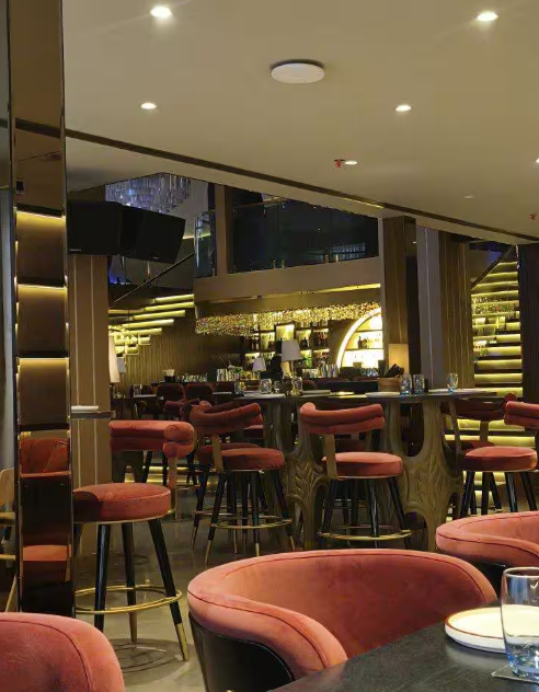 Conceived by Gauri Khan Designs, the interior floor plan relies on deep burgundy paneling, plush velvet tufted banquettes, and brass-trimmed vintage fixtures that feel reminiscent of a hidden Parisian salon. Overhead, amber chandeliers and warm accent spotlights illuminate every seating nook, turning every course into a focal visual event. Architectural glass elements, private curtained dining alcoves, and an interactive live Teppanyaki station create an energetic backdrop where soft jazz and DJ rhythms seamlessly complement the avant-garde food service.