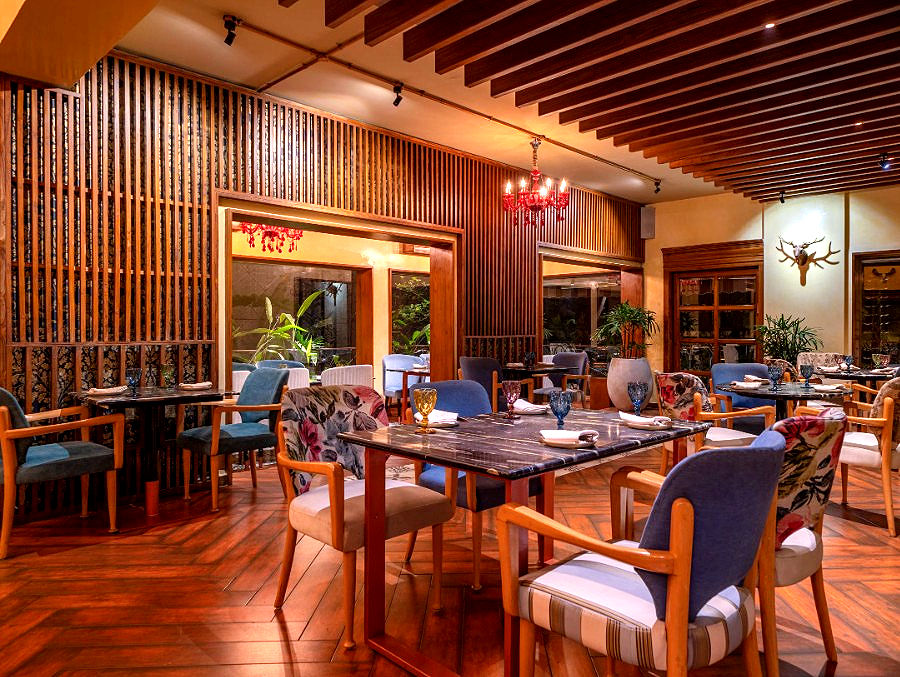 Conceived by architect Gokul Krishna (W Design Studio), it is among the restaurants in Hyderbad that prioritizes raw granite, reclaimed timber accents, mood-centric lighting, and curtained cabana clusters that feel like a hidden garden retreat rather than a standard commercial eatery. Focused warm spotlights illuminate each table to highlight the multi-course spread. Keeping urban noise at bay so the food and surroundings remain the main event, water features and dense tropical canopies frame the central dining arena.