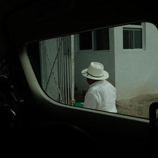 Fuji 23mm f2 | black and white street photo of a man in a hat from the view of a car