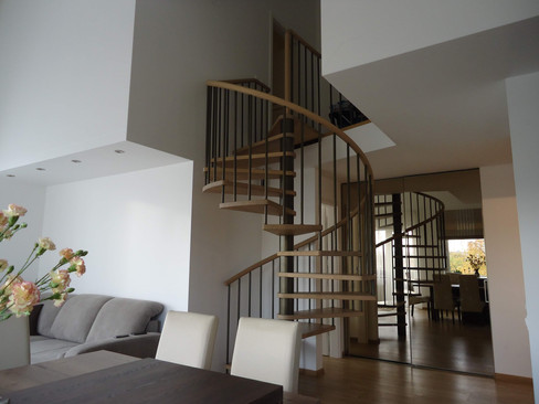 Delicate spiral staircase with a steel beam in the middle, steps from oak and handrails from steel stripes.