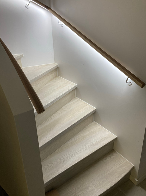 Solid construction U-shape staircase with oak stairs and LED lightning under the oak handrail.