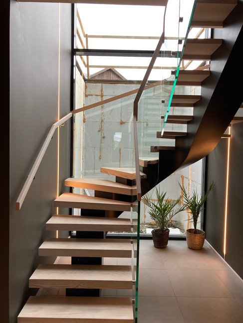 3-floor staircase with black steel construction and glass railings.