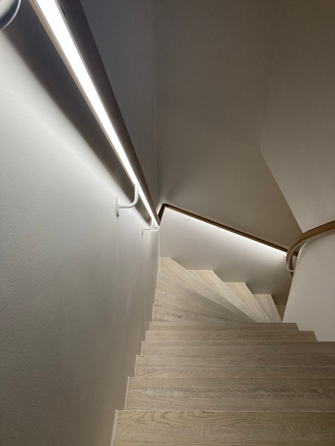 Solid construction U-shape staircase with oak stairs and LED lightning under the oak handrail.