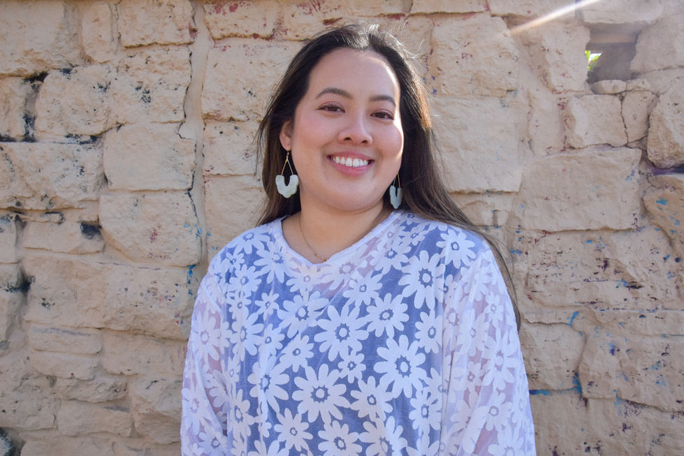 Eleanor is an Asian woman wearing a white daisy patterned top with short sleeves and her hair is blowing in the wind. She is wearing earrings from kaolee shop.