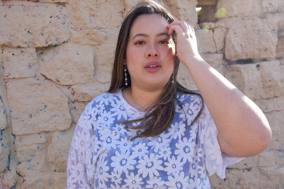 Eleanor is an Asian woman wearing a white daisy patterned top with short sleeves and her hair is blowing in the wind. She is wearing pearl drop earrings from kaolee shop.