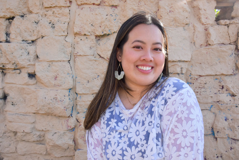 Eleanor is an Asian woman wearing a white daisy patterned top with short sleeves and her hair is blowing in the wind wearing Kaolee Shop polymer clay earrings