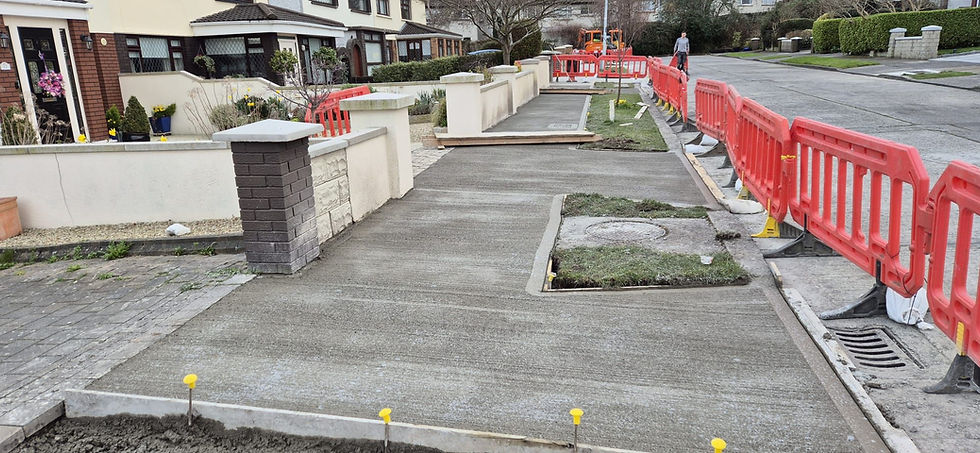 Freshly laid concrete footpath on residential street with safety barriers, local authority works by Formac Construction Leinster