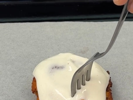 single serve cinnamon roll with a fork coming in for a bite