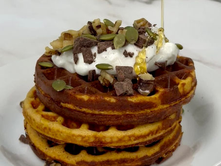 stack of protein pumpkin waffles topped with protein yogurt and pumpkin seeds