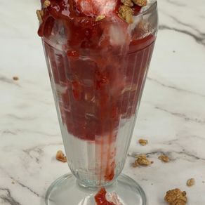 ice cream sundae with strawberry rhubarb dessert sauce and a crunchy oat crumble topping