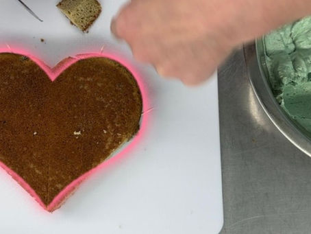top view of a heart shaped cake and a bowl of green icing