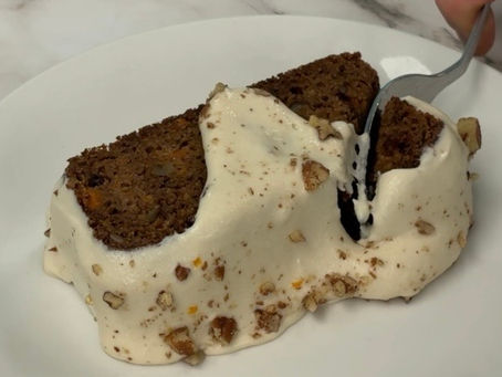 fork cutting into a slice of carrot cake loaf, topped with cashew cream cheese
