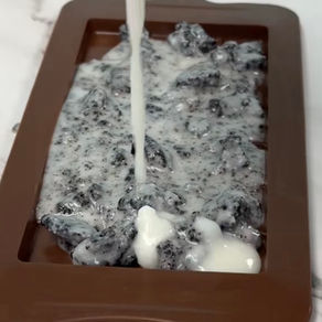 pouring a white chocalte cookies & cream chocolate bar into a mold