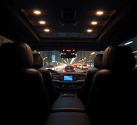 Interior of a luxury black SUV at night, rear passenger view — plush leather seats, ambien