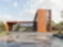 Contemporary corten steel building with large glass facade and bold geometric form.