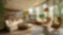 Tropical style living room with a cream sectional sofa, woven pendant lights, rattan coffee table, lounge chairs, indoor plants, and floor to ceiling windows overlooking greenery.