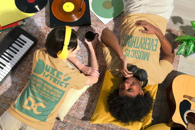 Two people listening to records, wearing Duke's District merchandise
