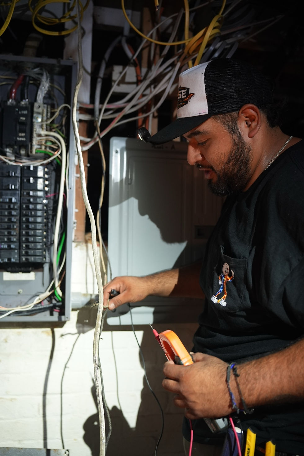 Fase Electric team member using electrical test equipment beside a panel