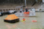Zwei Personen auf einem Sportboot retten eine Person im Wasser
