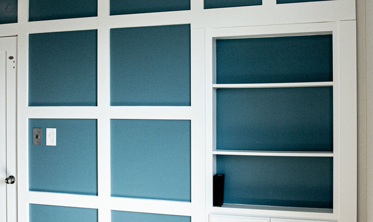 Custom hidden door integrated into a paneled wall with blue insets.