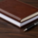 Brown leather notebook and pen for regulatory compliance consulting