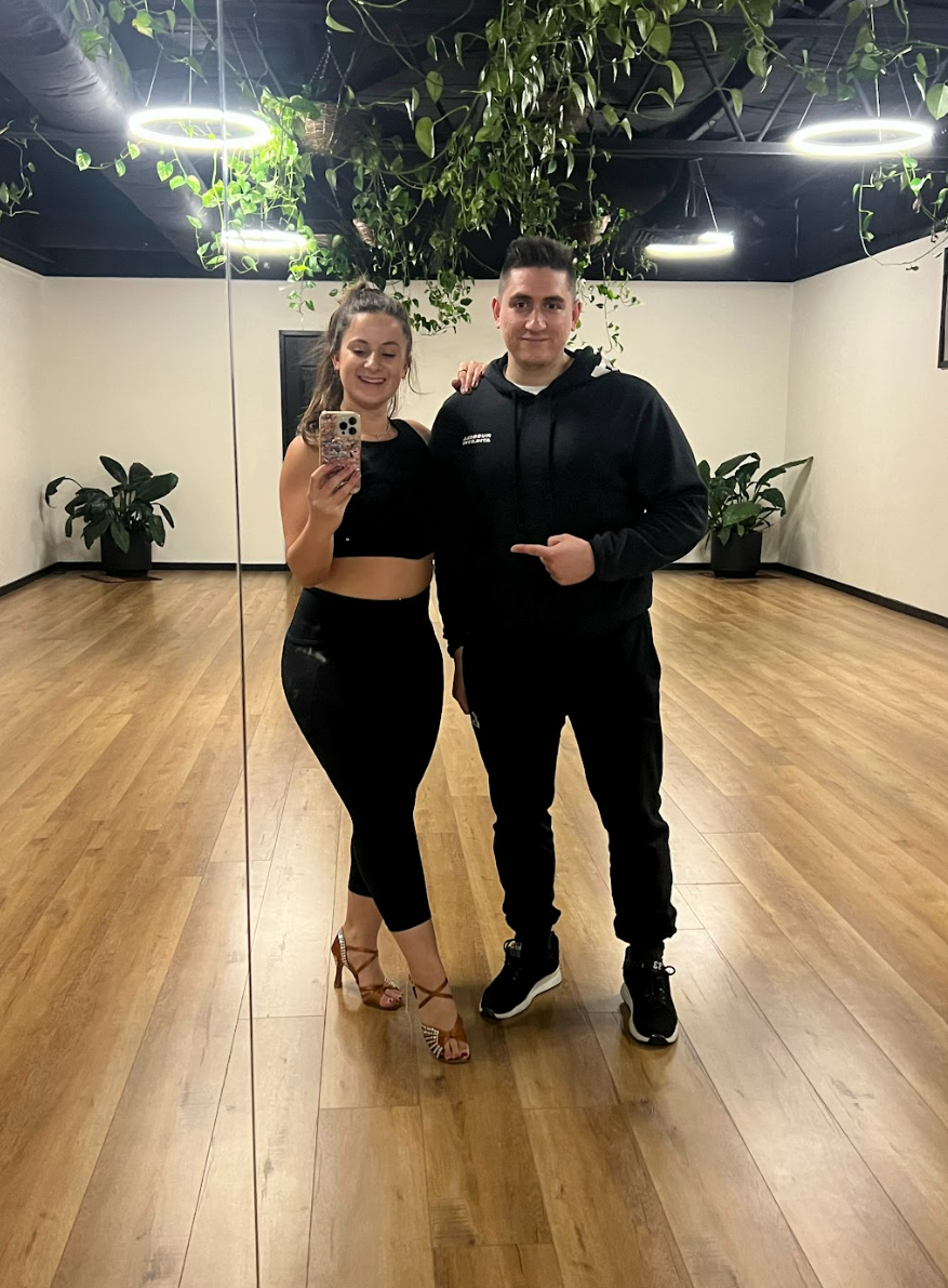 Dance student and his instructor posing for photo in front of mirror