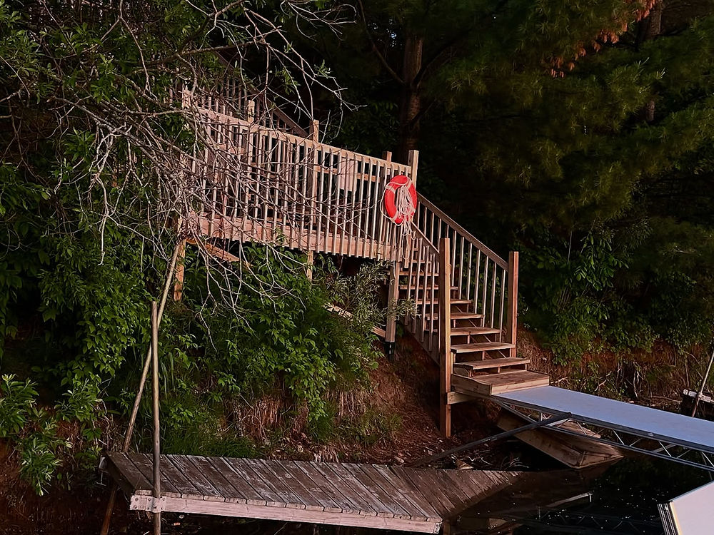 Wooden stairs and platform leading to a dock with a red life ring