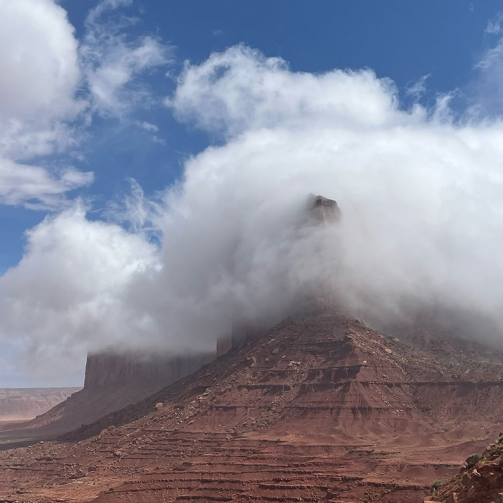 A plateau is engulfed in a cloud with a blue sky overhead