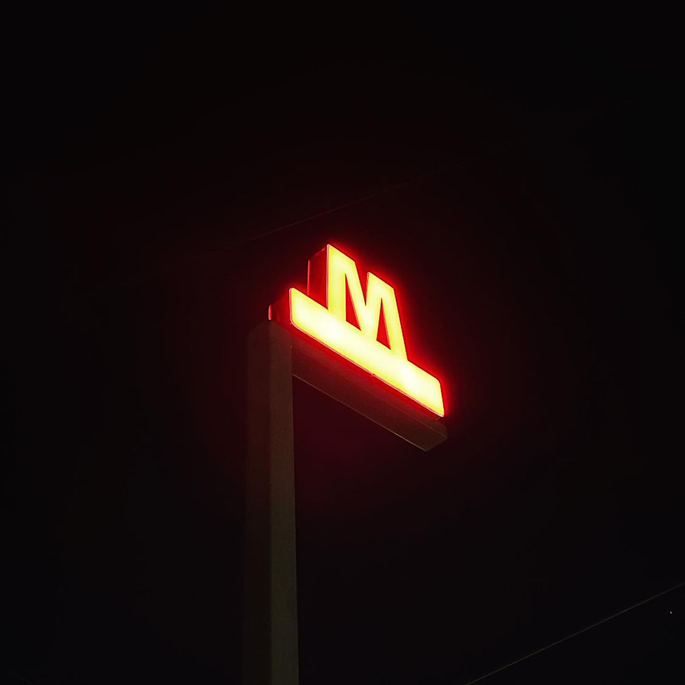 Red illuminated Copenhagen metro sign 'M' at night