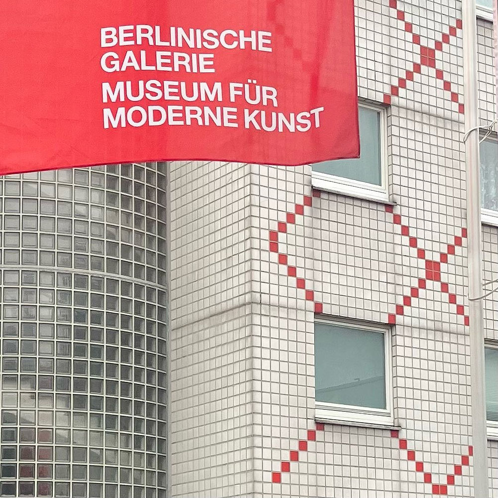 Red banner for Berlinische Galerie Museum for Modern Art in front of a glass and tiled building wall