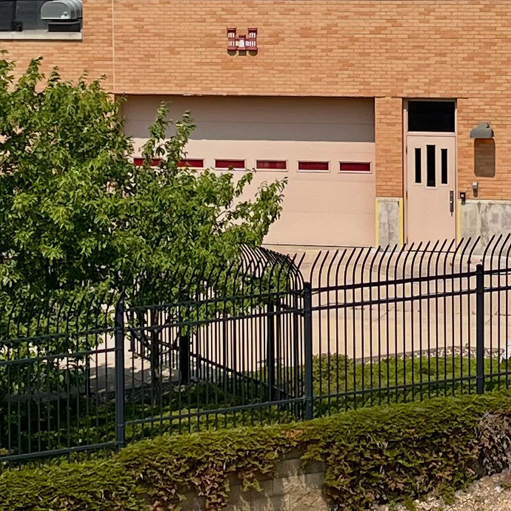 Brick building with beige garage door and black fence