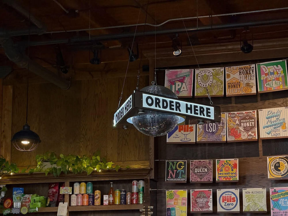 ORDER HERE sign on a disco ball in a store with colorful art on the wall