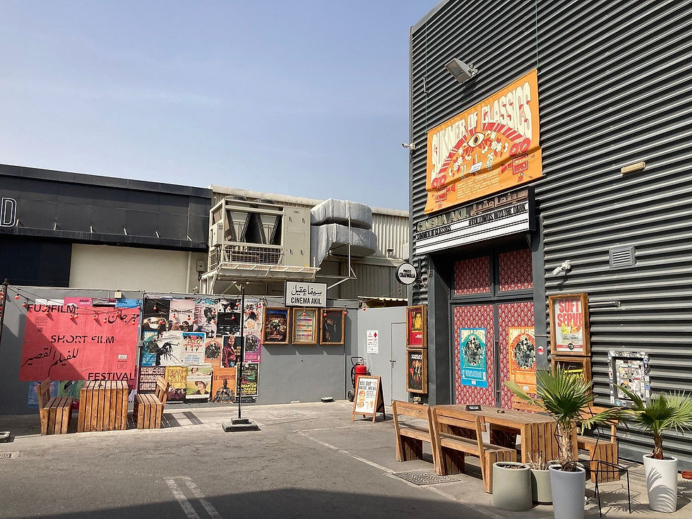 Outdoor cinema entrance with colorful posters, a "SUMMER OF CLASSICS" banner, wooden benches, and potted plants; festival signage visible.