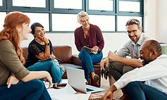 A team of diverse people seated around a laptop